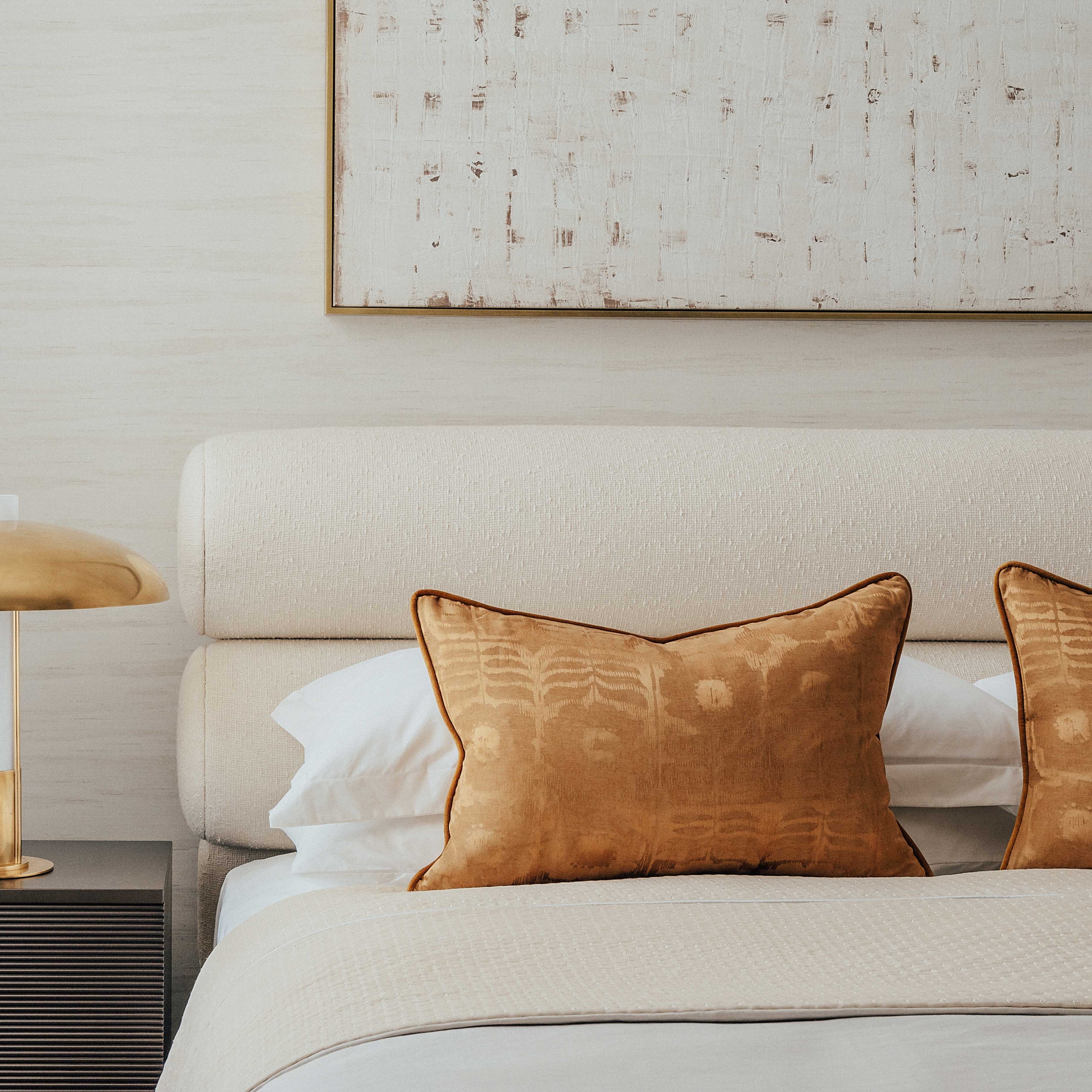 A Northumberland bed with beige linen bouclé upholstery, featured in a serene bedroom setting with white curtains and brown accent pillows. The OWO