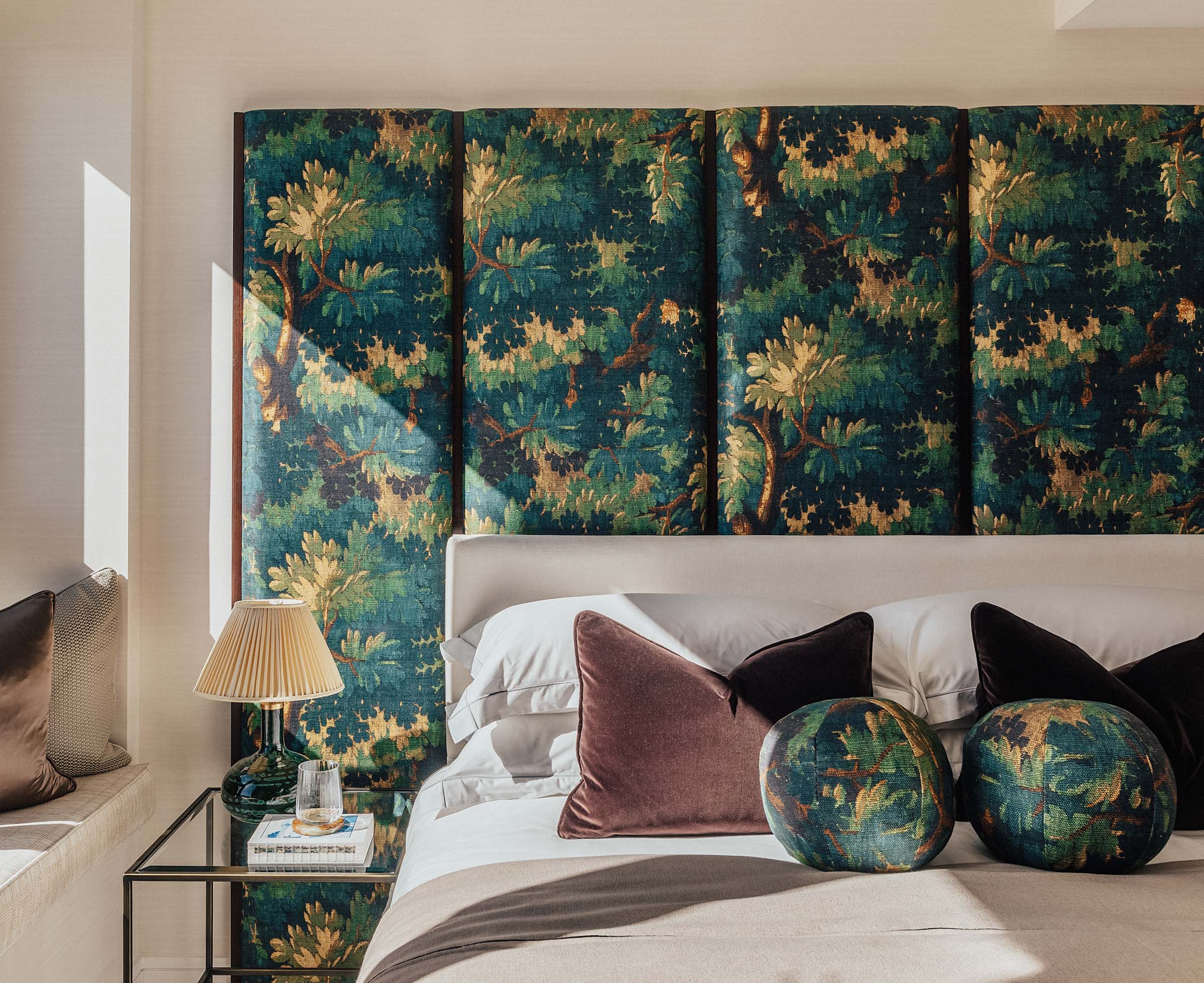 Bedroom with oversized decorative headboard featuring a forest design, pillows, and a lamp.